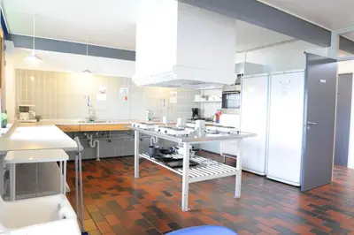 a large kitchen with white appliances and a table at Danhostel Nykøbing Mors in Nykøbing Mors