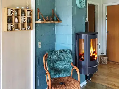 a fireplace in a living room with a chair with a blanket at 5 person holiday home in Vinderup-By Traum in Vinderup