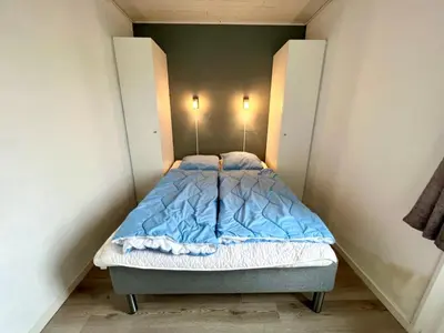 a small bed in a small room with two doors at Agger Tange Feriecenter lejligheder - 100 m fra Vesterhavet in Vestervig