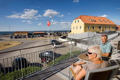 two people sitting on a balcony looking at a parking lot at Hvalpsund Færgekro in Hvalpsund