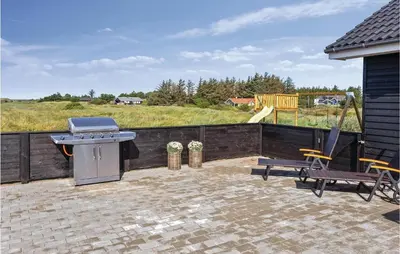 a grill and two chairs on a patio with a playground at 8 Bedroom Awesome Home In Thisted in Thisted
