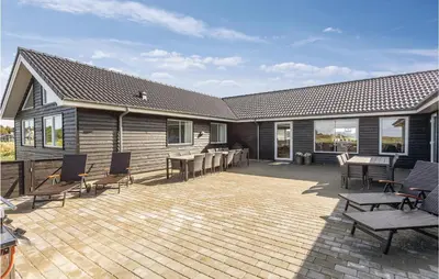 a house with a patio with chairs and a table at 8 Bedroom Awesome Home In Thisted in Thisted