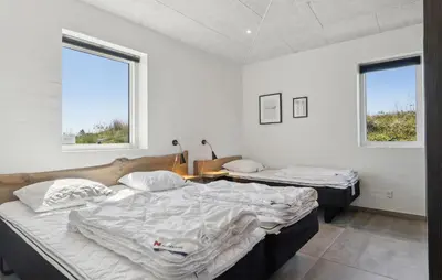 two beds in a room with two windows at Nice Home In Thisted With Sauna in Thisted