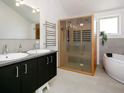 a bathroom with two sinks and a shower and a tub at Modern Retreat with Spa - By Traum Ferienwohnungen in Løkken