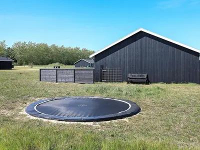 a trampoline in a field next to a building at Modern Retreat with Spa - By Traum Ferienwohnungen in Løkken