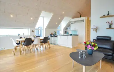 a living room with a table and chairs and a kitchen at Two-Bedroom Apartment In Thisted in Thisted