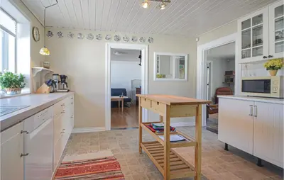 a kitchen with white cabinets and a wooden table at Three-Bedroom Holiday Home In Vinderup in Vinderup