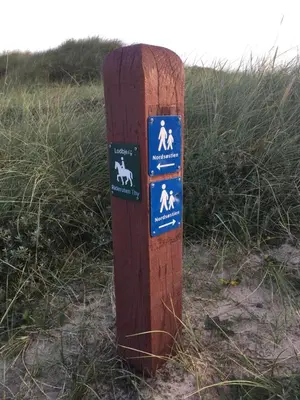 a wooden post with signs on it in the grass at Bulbjerguld BB in Frøstrup