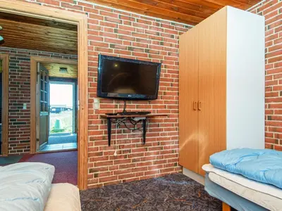 a room with a brick wall with a tv on a wall at 14 person holiday home in Harboøre in Harboør