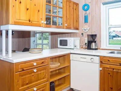 a kitchen with wooden cabinets and a white microwave at 6 person holiday home in Thisted-By Traum in Thisted