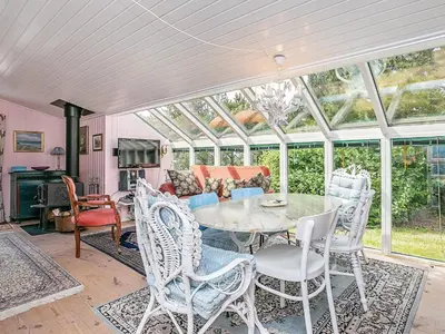 a conservatory with a table and chairs and a couch at Holiday Home with Terrace & Fire Pit in Thisted