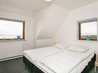 a white bedroom with a bed and two windows at Seaside Retreat in Hvalpsund-By Traum in Farsø