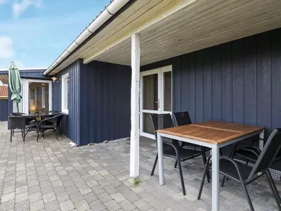a patio with a wooden table and chairs on it at Cozy Coastal Retreat in Vorupor-By Traum in Thisted