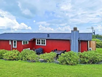 a red house with a black roof in a field at 6 person holiday home in Lemvig in Lemvig