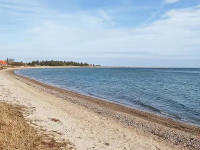 a sandy beach with water and trees in the distance at 6 person holiday home in Lemvig in Lemvig