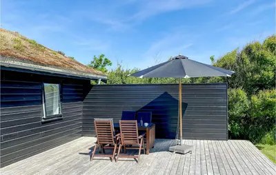 a table and two chairs under an umbrella on a deck at Beautiful Home In Blokhus With Kitchen in Blokhus