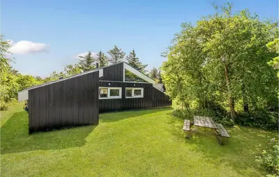 a black house with a bench in the yard at Nice Home In Vestervig With Wifi in Vestervig