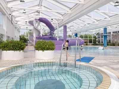 a swimming pool with a purple slide in a building at Vegsø Holiday Park Premium Retreat in Hanstholm