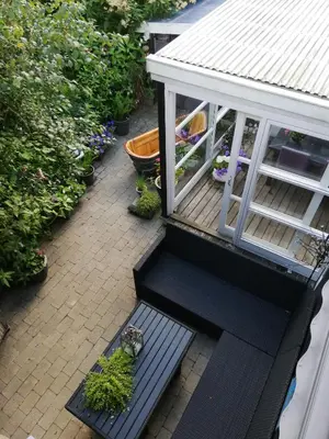 a porch with a black bench and some plants at Hunetorpvej Holiday Apartment in Blokhus