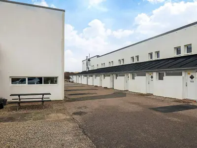 a row of white buildings with a bench in a parking lot at 6 person holiday home in Brovst in Brovst