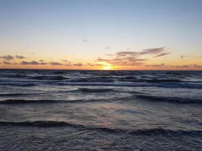 a sunset over the ocean with waves at 6 person holiday home in Brovst in Brovst