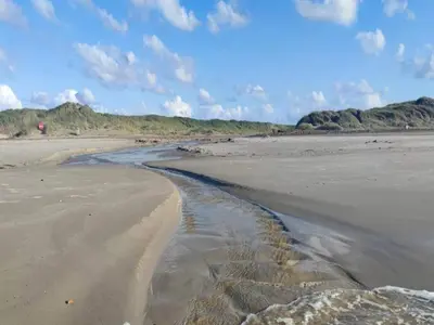 a beach with a stream of water in the sand at 6 person holiday home in Brovst in Brovst