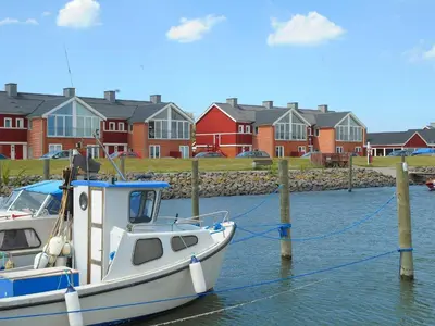 a boat docked in the water in front of houses at 5 person holiday home on a holiday park in Lemvig in Lemvig