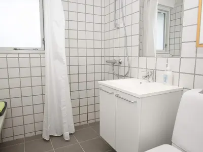 a white bathroom with a sink and a mirror at Room in Vigsø Holiday Park in Hanstholm