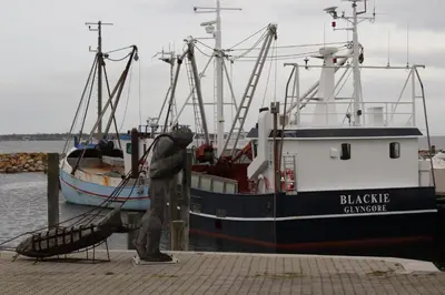 a statue of a man standing next to a boat at Glyngøre Camping in Glyngøre