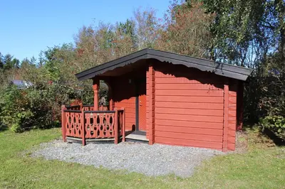 a red shed with a black roof in the grass at Glyngøre Camping in Glyngøre