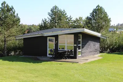 a small black shed with a picnic table in a field at Glyngøre Camping in Glyngøre