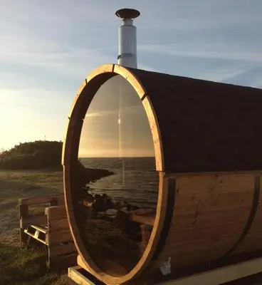 a wooden circular building with a window on the beach at Rødhus Gl. Skole B&B in Pandrup