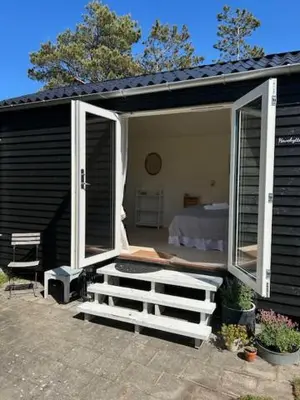 a black house with an open door and a bed at Rødhus Gl. Skole B&B in Pandrup