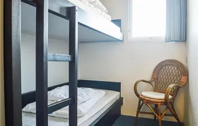 a bedroom with a bunk bed with a chair and a chair at Feriehotel Tranum Klit in Brovst
