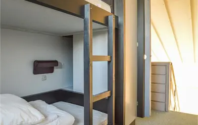 a bedroom with a bunk bed and a ladder to a bunk bed at Feriehotel Tranum Klit in Brovst