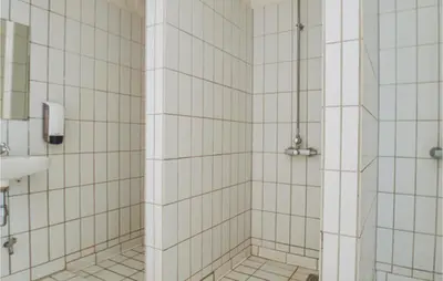 a bathroom with a shower with white tiled walls at Feriehotal Tranum Klit in Brovst