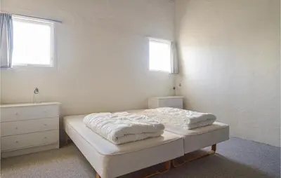 a bedroom with a bed and a dresser and two windows at Feriehotal Tranum Klit in Brovst