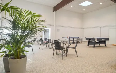 a room with ping pong tables and chairs and a plant at Feriehotel Tranum Klit in Brovst
