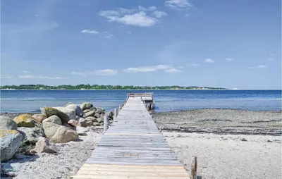 a wooden pathway leading into the water on a beach at Fjordens Perle in Farsø