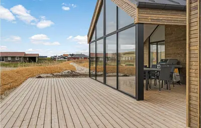 a house with a wooden deck with a table at Nice Home In Harboøre With Sauna in Harboør