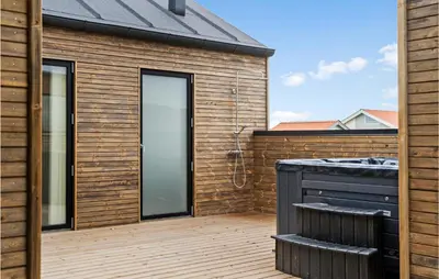 a wooden deck with a hot tub and a house at Nice Home In Harboøre With Sauna in Harboør