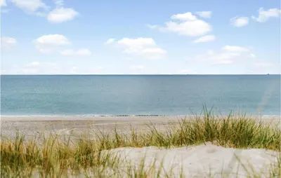 a beach with a view of the ocean and grass at Nice Home In Harboøre With Sauna in Harboør