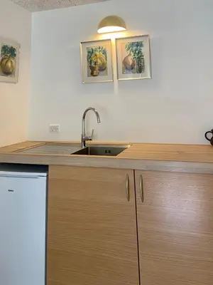 a kitchen with a sink and two pictures on the wall at Anne Just's Havehotel in Blokhus