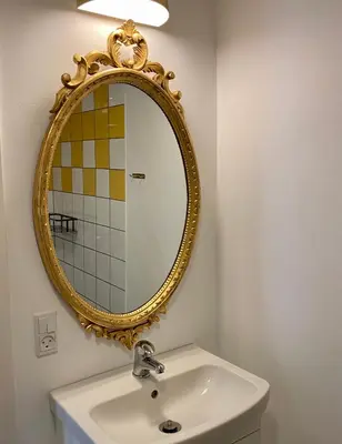 a bathroom with a gold mirror above a sink at Anne Just's Havehotel in Blokhus
