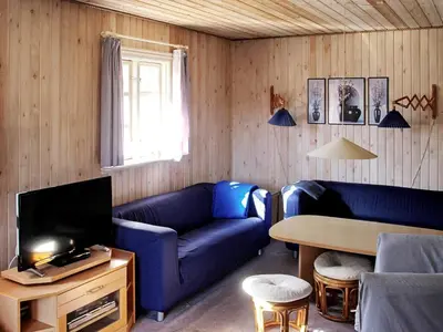 a living room with a blue couch and a table at Secluded Forest Retreat at Gjol-By Traum in Åbybro