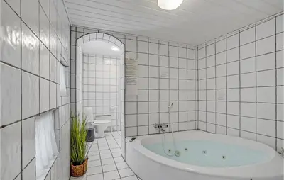 a white tiled bathroom with a tub and a toilet at Nice Home In Thisted With Sauna in Thisted