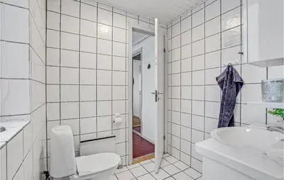 a white tiled bathroom with a toilet and a sink at Nice Home In Thisted With Sauna in Thisted