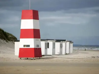 a red and white lighthouse on the beach at 6 person holiday home in Blokhus in Blokhus