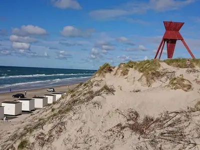 a red structure sitting on top of a sandy beach at 6 person holiday home in Blokhus in Blokhus