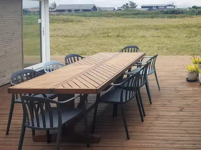 a wooden table and chairs on a deck at 6 person holiday home in Thisted in Torsted